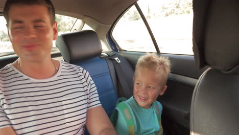 cheerful father and son traveling by car