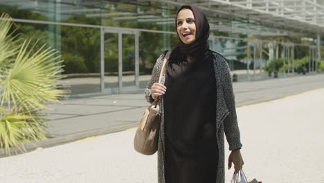 beautiful muslim woman walking in street with shopping bags.