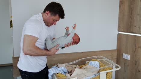 happy new-made father takes a tiny baby lying in the crib. father and newborn son in the hospital ward.