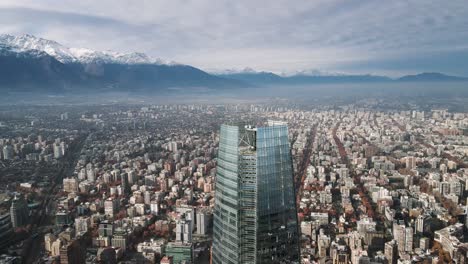 close-up aerial view of an orbit with buildings in santiago, chile and the snow-capped andes mountains in winter