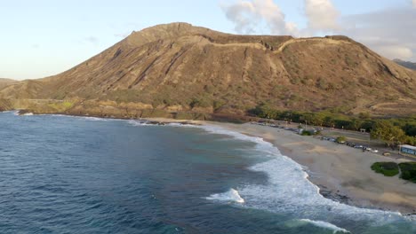 Sandstrand-Oahu-Hawaii-Koko-Head-Im-Hintergrund-Krachende-Wellen-Am-Strand