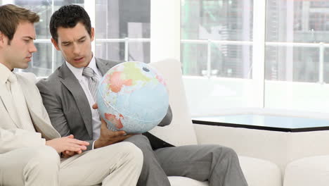 businessmen looking at a terrestrial globe