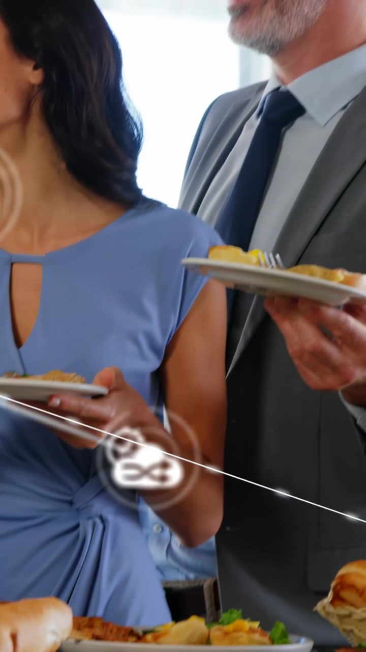 Video vertical: Colegas hablando en un buffet, generando nodos de interfaz de usuario sobre los platos, con rostros mapeando enlaces de negocios.