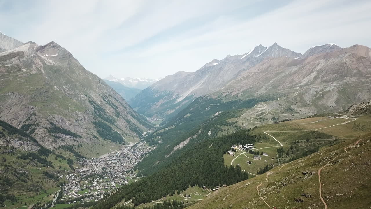paisaje de los alpes suizos: montañas rocosas, campos floridos, bosque de abetos, ruta de senderismo y pueblo zermatt, vista aérea de drones