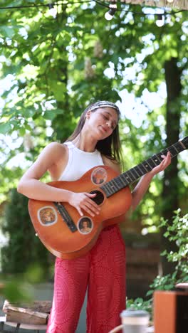 young woman playing acoustic guitar in a garden