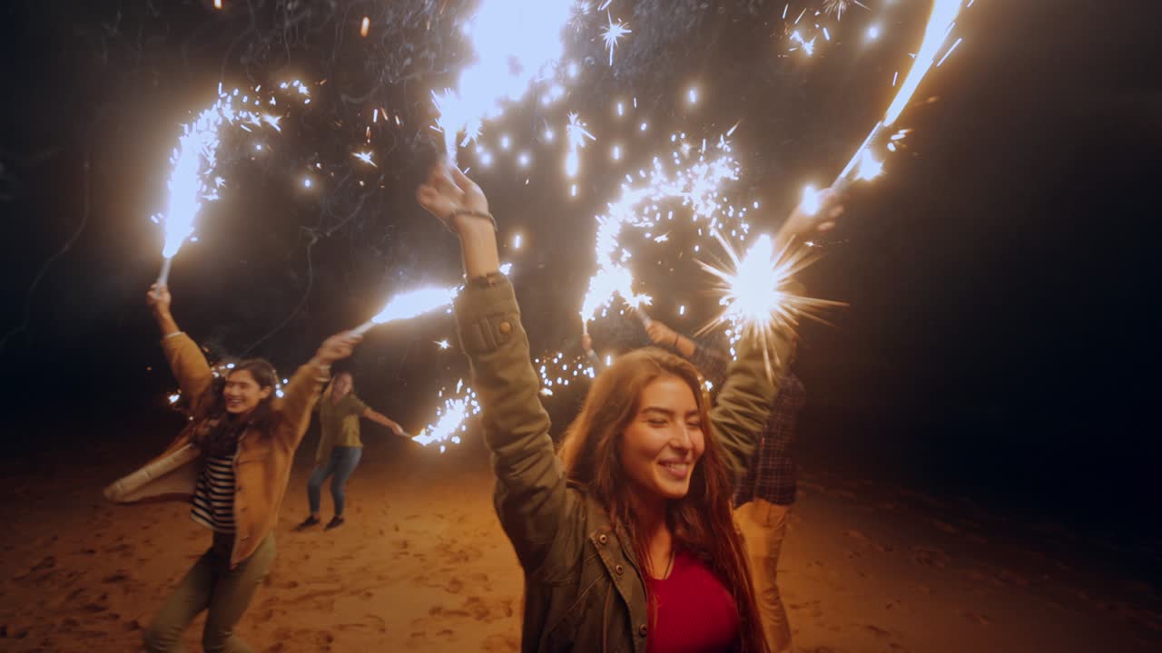 Group of friends having fun with sparklers at the beach