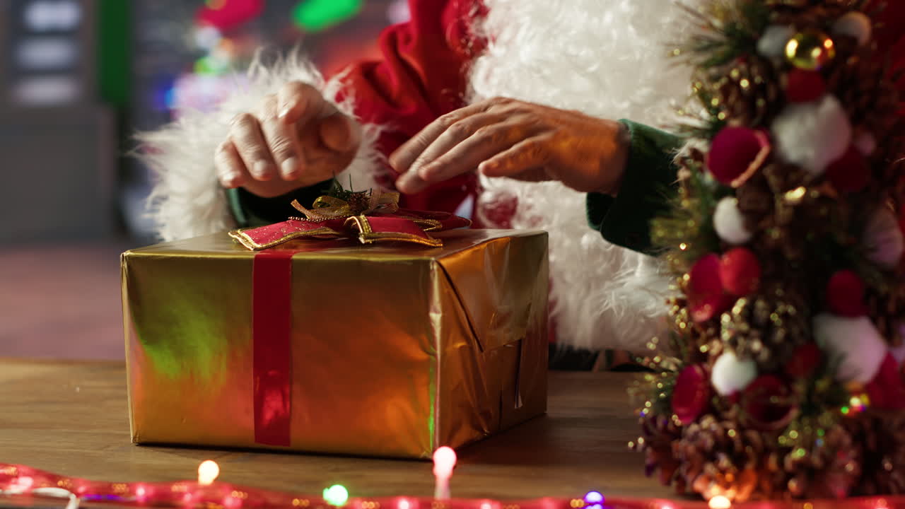 Santa Claus holding a Christmas present near a Christmas tree