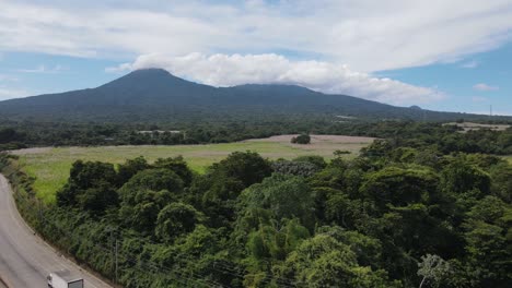 panning to the right of a panoramic view of an area with a lot of vegetation and a tall volcano in the background