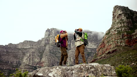 two senior men celebrate on top of mountain