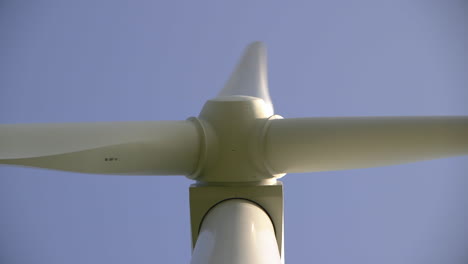 close upward look along the shaft of a spinning wind turbine