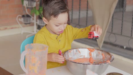 Ein-Kleiner-Junge,-Der-Mit-Teig-Und-Spielzeugautos-Spielt-Und-Spaß-Hat