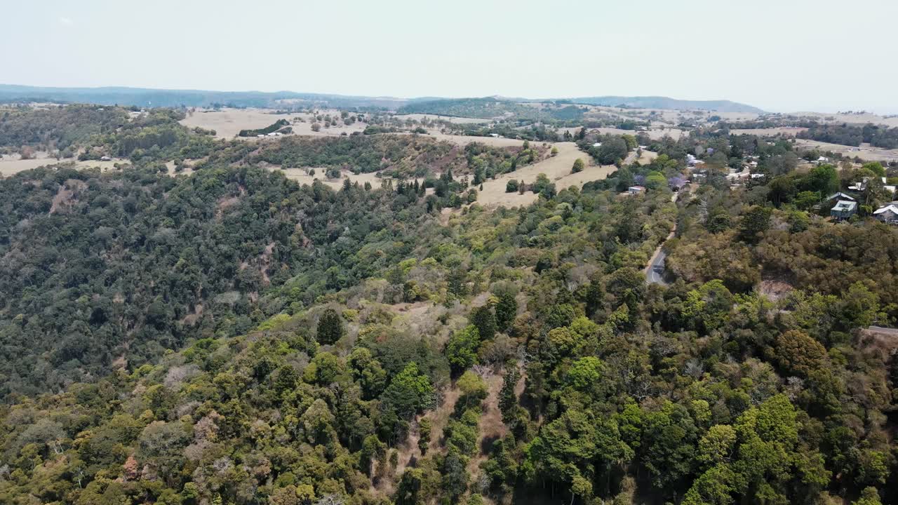 drone aéreo sobre una exuberante montaña nativa australiana con árboles y casas