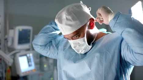 Biracial-male-surgeon-wearing-face-mask-in-operating-theatre,-slow-motion