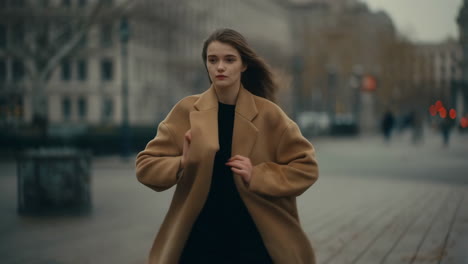 young woman walking in a city street in a beige coat