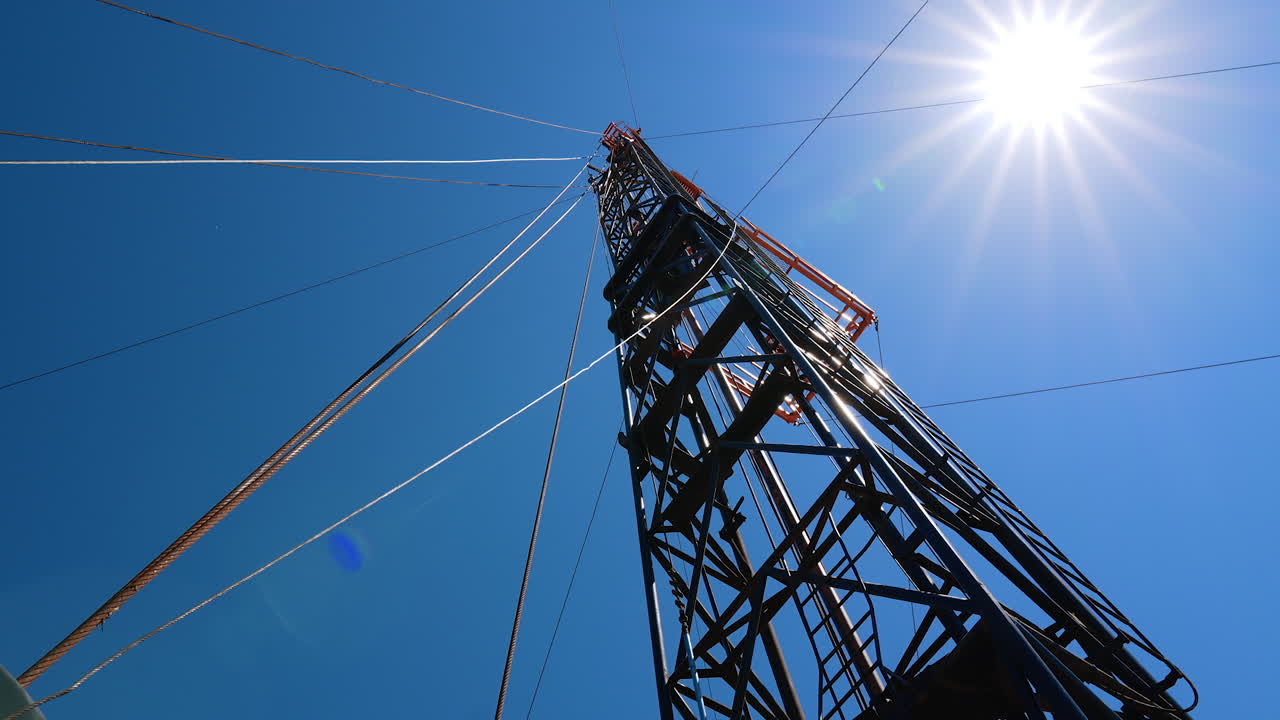 Metal wires are attached to the metal support from different sides. Low angle view on the tower for drilling resources.