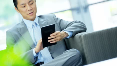 asian american businessman in office atrium with tablet