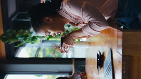 vertical video of young businesswoman with coffee working on laptop sitting in coffee shop