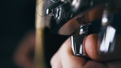 el guitarrista afina una nueva guitarra acústica con cabeza negra.