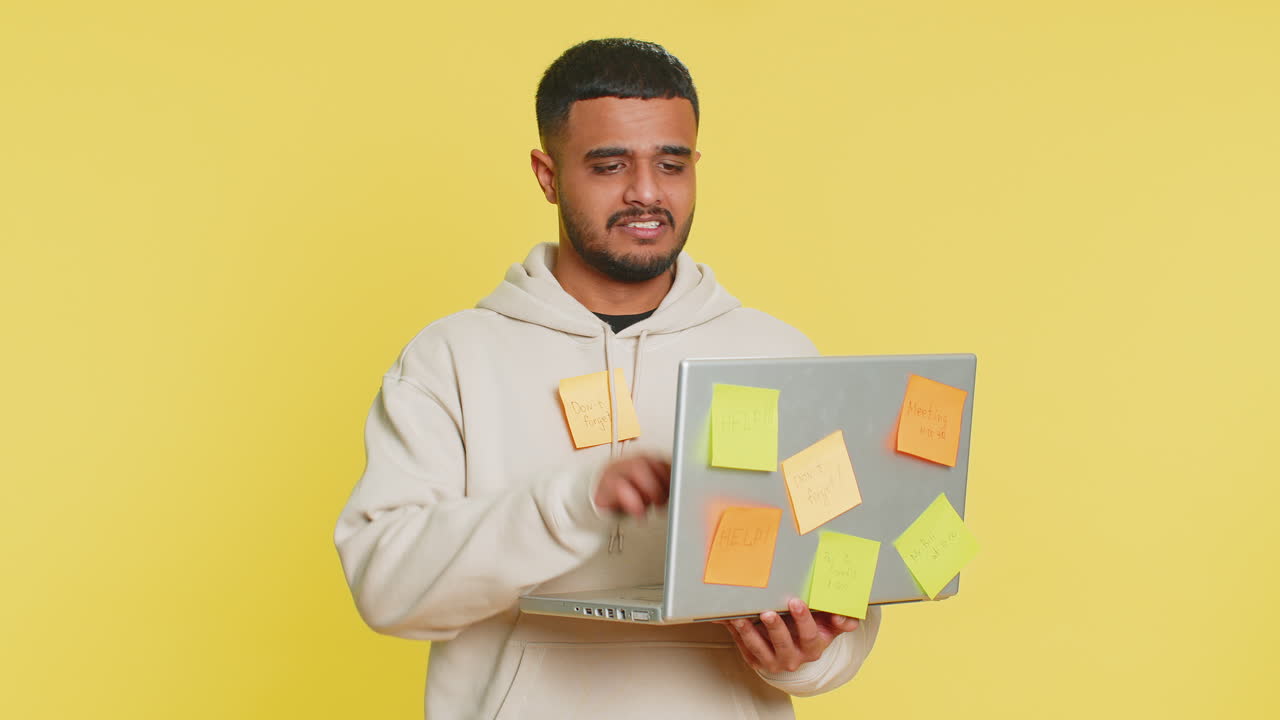 Indian young man with pasted sticker notes use laptop having concentration problem big routine work