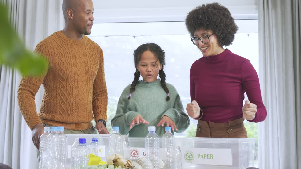 African American family starting recycling at table, guiding girl through sorting bottles into bins