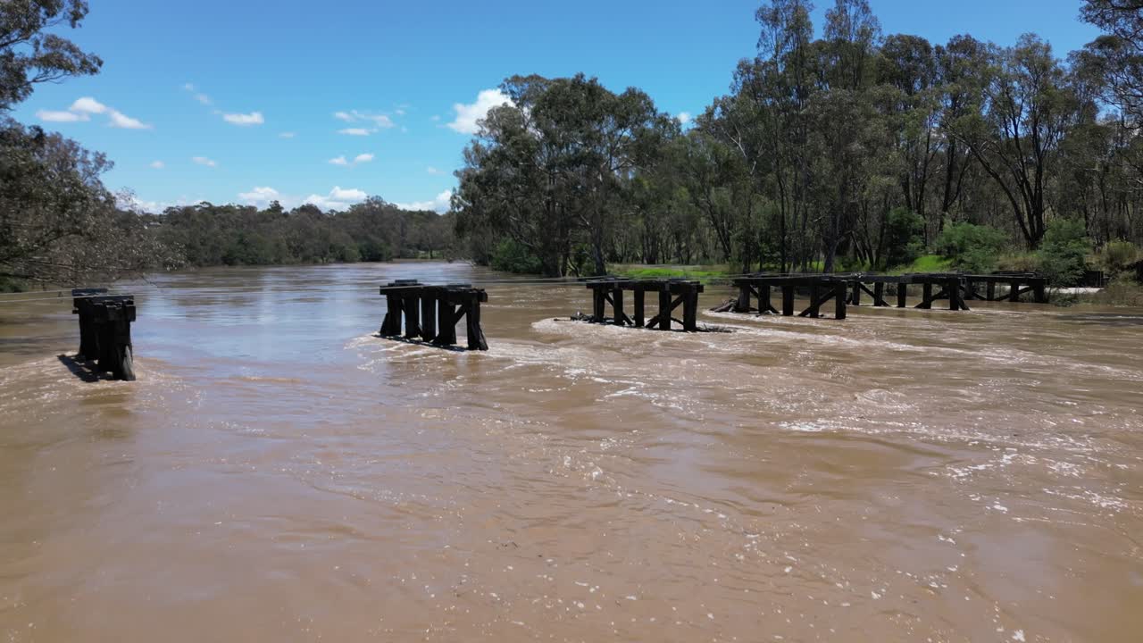 drone de panela baja del río goulburn inundado con viejo puente en fuertes corrientes de carreras