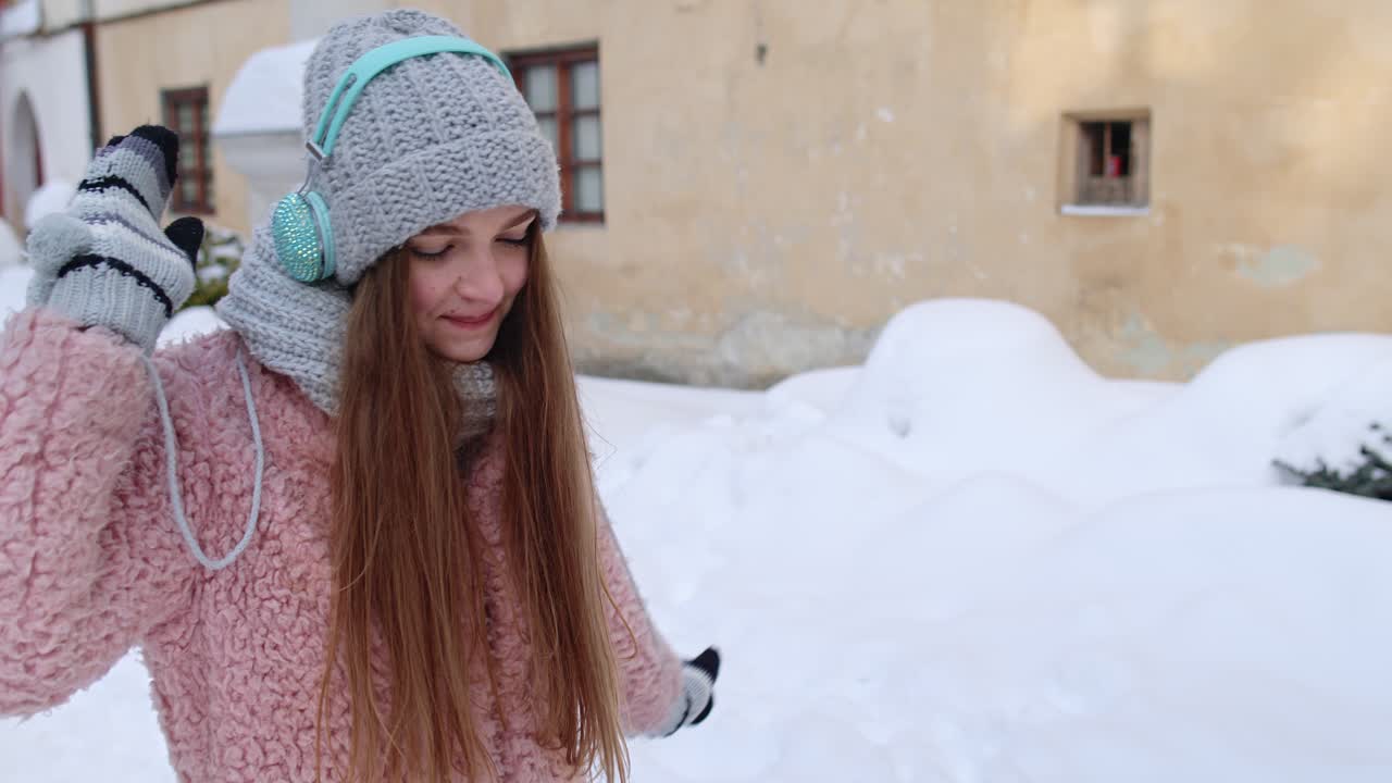 chica turista durante sus vacaciones escuchando música a través de auriculares y bailando en el centro de la ciudad vieja