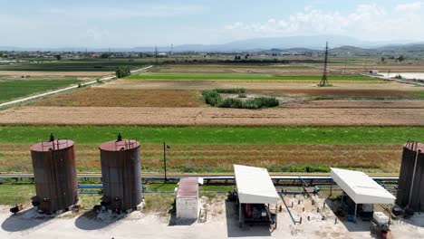 panoramic shot of industrial oil tanks next to farming fields causing pollution