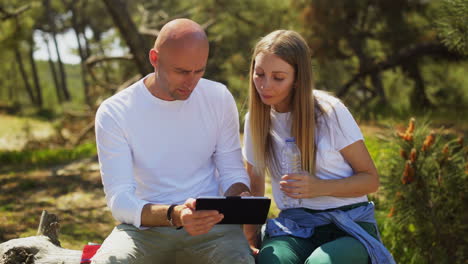 pareja usando una tableta digital en el bosque
