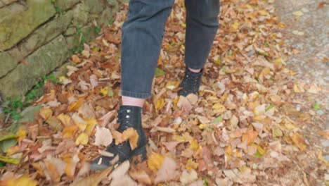 Feet-slowly-kick-fallen-golden-autumn-leaves-Legs-close-up-track-back