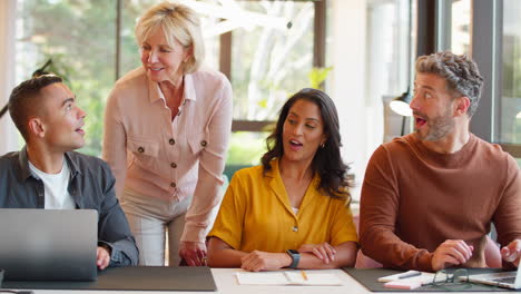 multi-cultural business team meeting around laptop in modern office