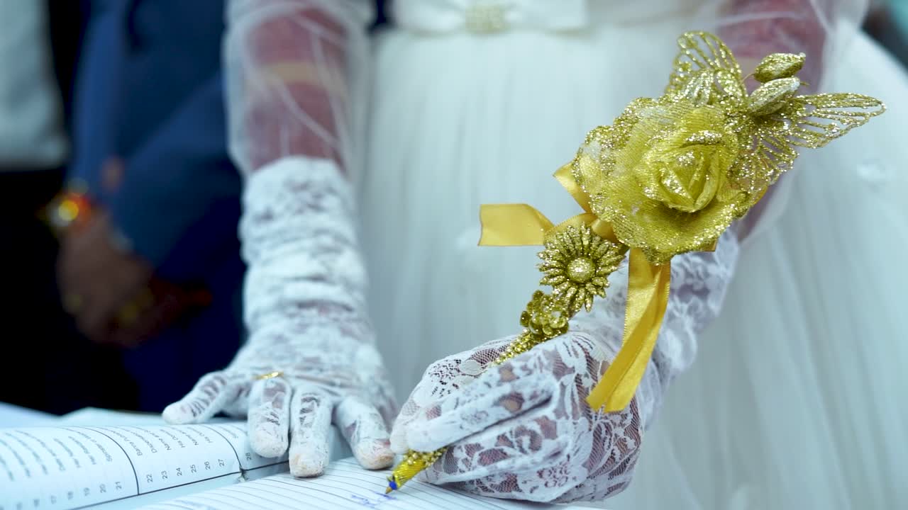 La sposa sta firmando il contratto di matrimonio con una penna d'oro splendidamente decorata