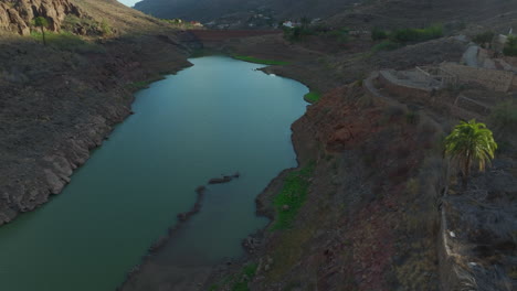 Ayagaures-dam,-Gran-Canaria:-aerial-view-traveling-in-the-retaining-wall-of-the-dam-on-a-sunny-day