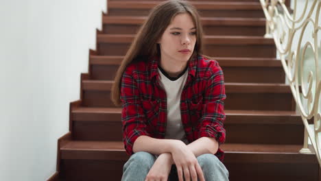 worried woman sits on staircase. student lost keys and waits for roommate to come in dormitory. lady expresses negative emotions in public place