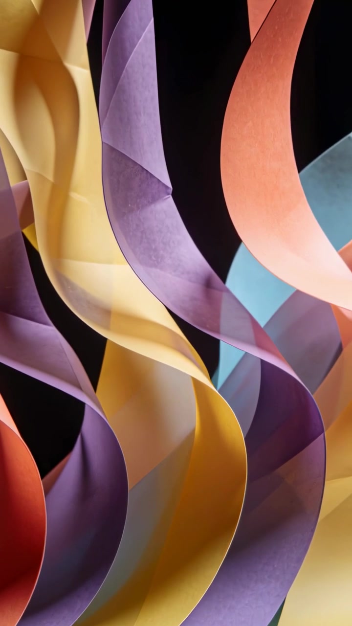 Vertical video: Shifting light revealing curled paper ribbons on black set exposing hidden curves