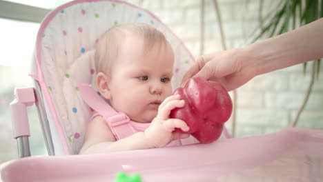 baby gnawing red pepper in chair. baby vegetable diet. healthy nutrition for kid