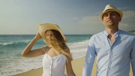 Couple-holding-hands-and-walking-on-sandy-beach