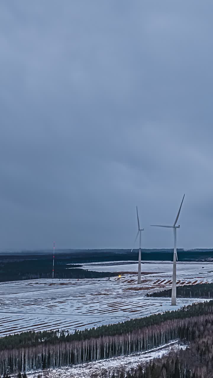 Vindmøller rager op over et snedækket landskab, fredfyldt og roligt.