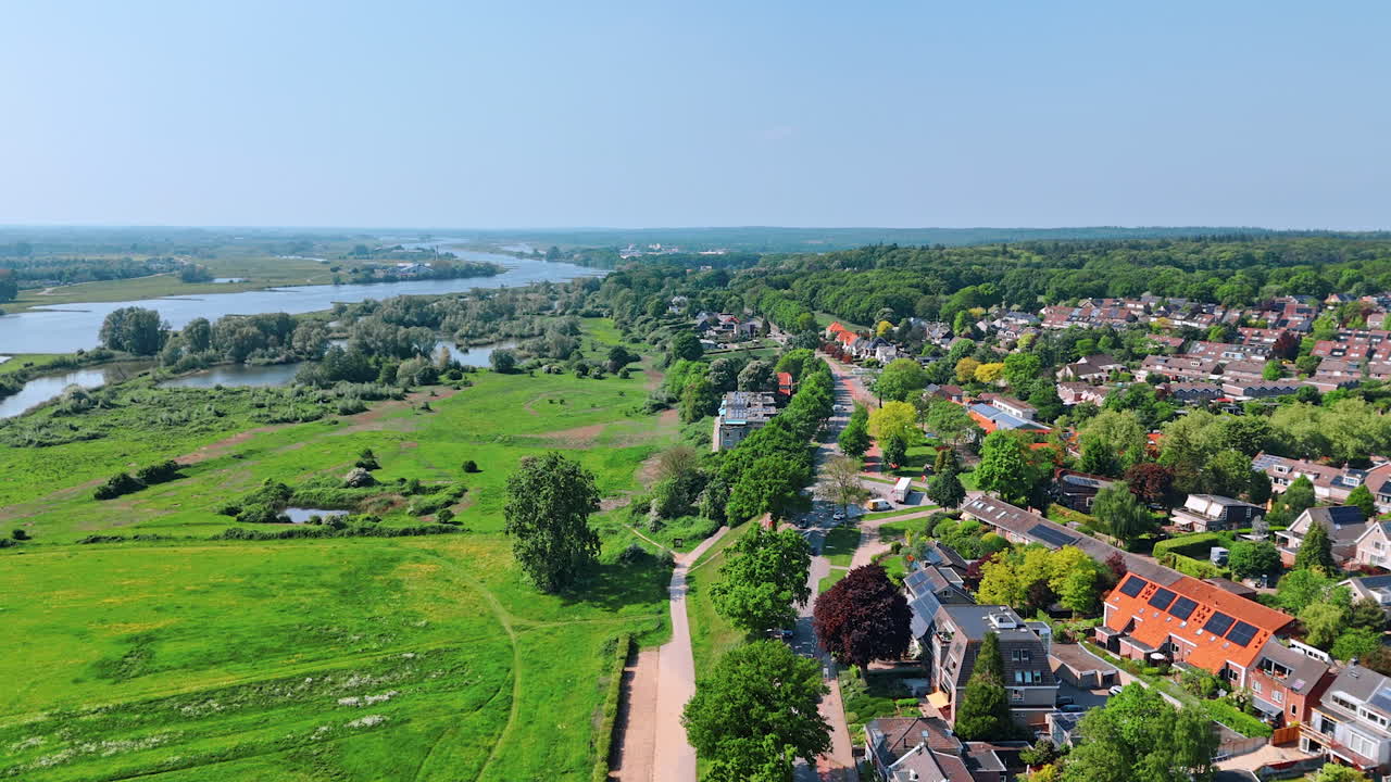 Cozy picturesque residential area at the waterfront of a narrow river. Flight above the countryside in the Netherlands on sunny day.
