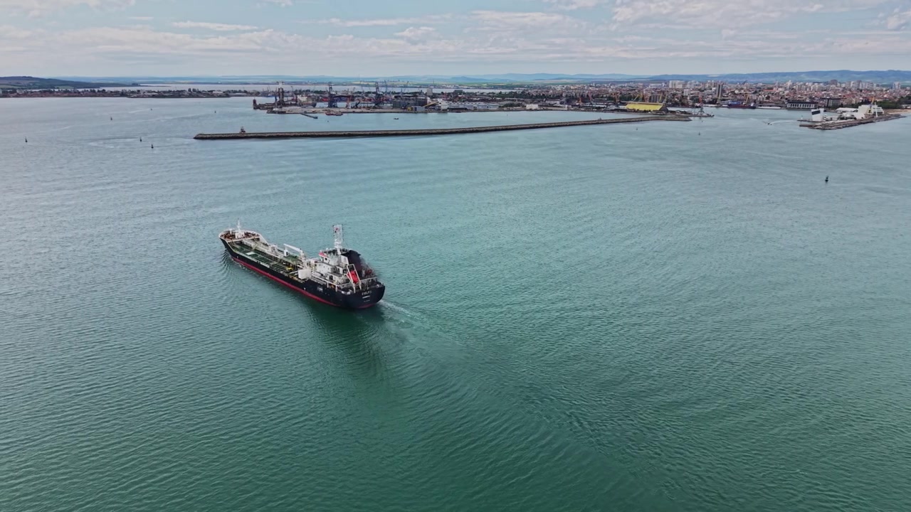 Large ship moves through water near harbor during afternoon hours