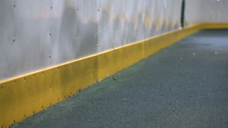 subtle reflection of a person visible on a metallic wall as a soccer ball hits the surface, with dynamic motion and impact captured under bright lighting in an urban sports setting