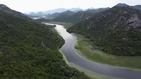 boat sails over crnojevica river to skadar lake at pavlova strana viewpoint, montenegro - aerial dolly