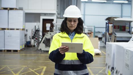 Serious-engineer-checking-equipment-while-walking-with-tablet