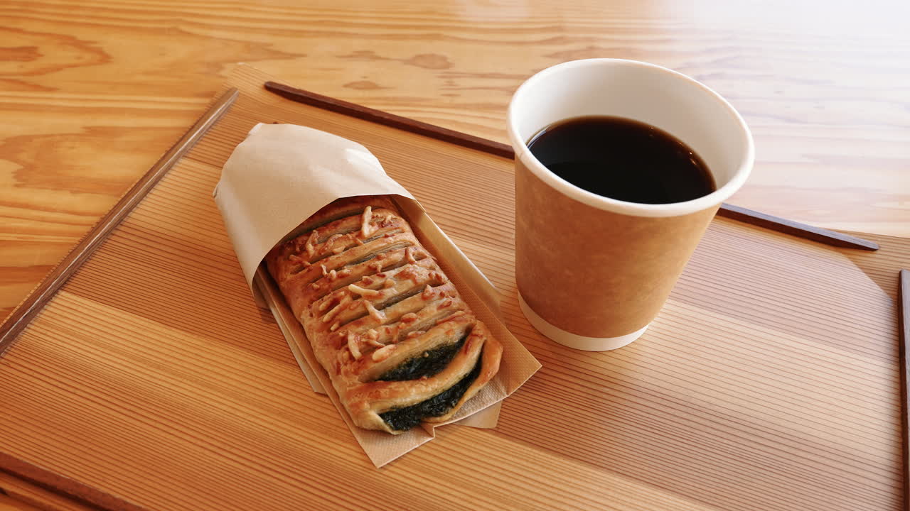 Fresh pastry and a hot black coffee on a wooden table