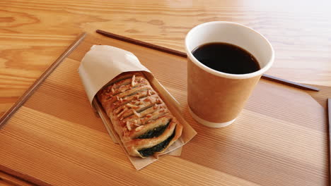 fresh pastry and a hot black coffee on a wooden table
