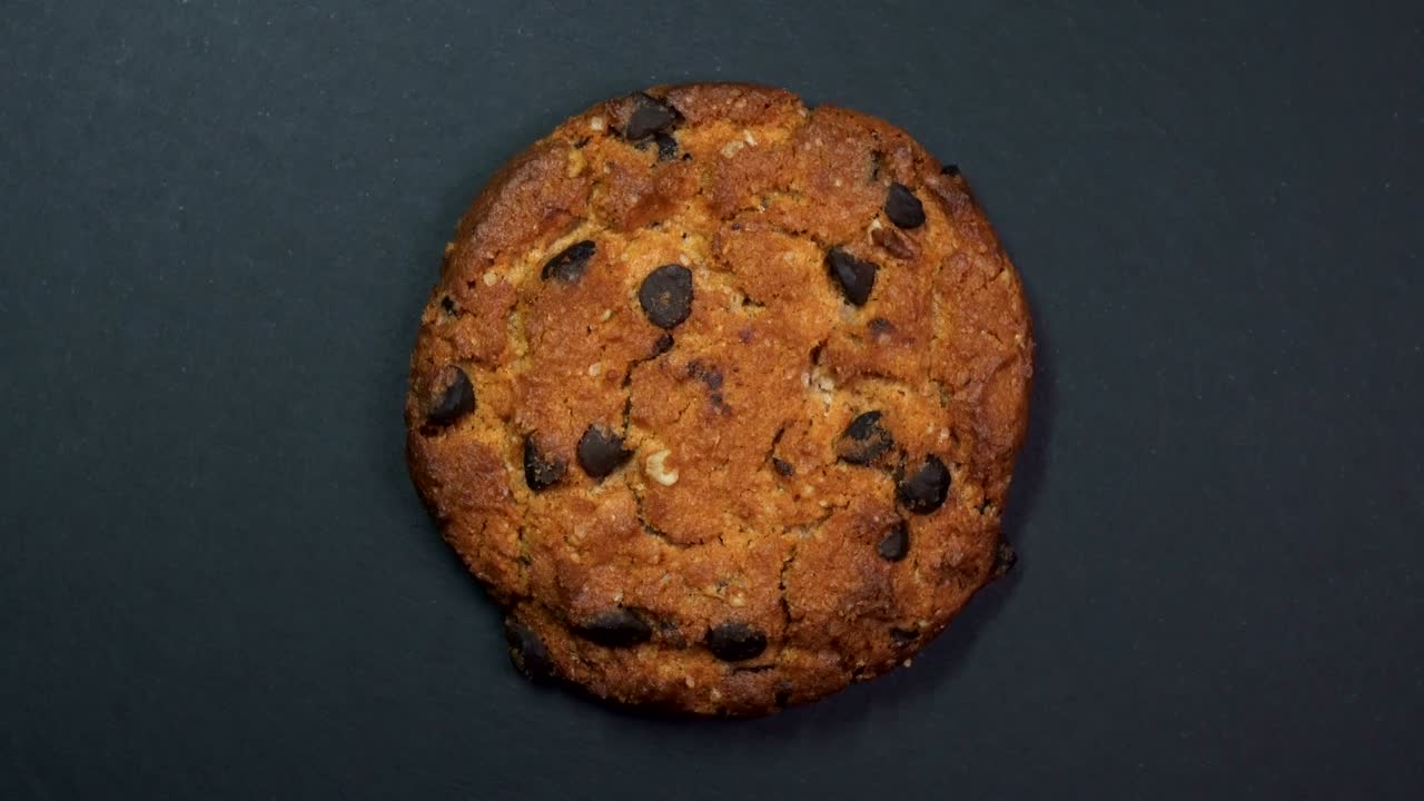 una galleta de chocolate en primer plano, una foto macro, girando rápidamente sobre un fondo negro giratorio.