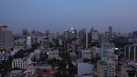 Aerial-view-of-Ho-Chi-Minh-City,-Saigon,-Vietnam-evening-tracking-across-key-buildings-of-skyline-from-the-city-center-under-lights