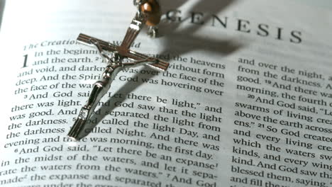 rosary beads falling onto the book of genesis