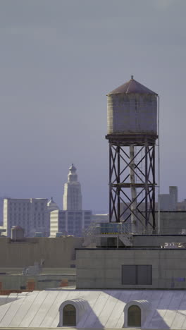 old water tower stands tall among modern buildings in urban skyline