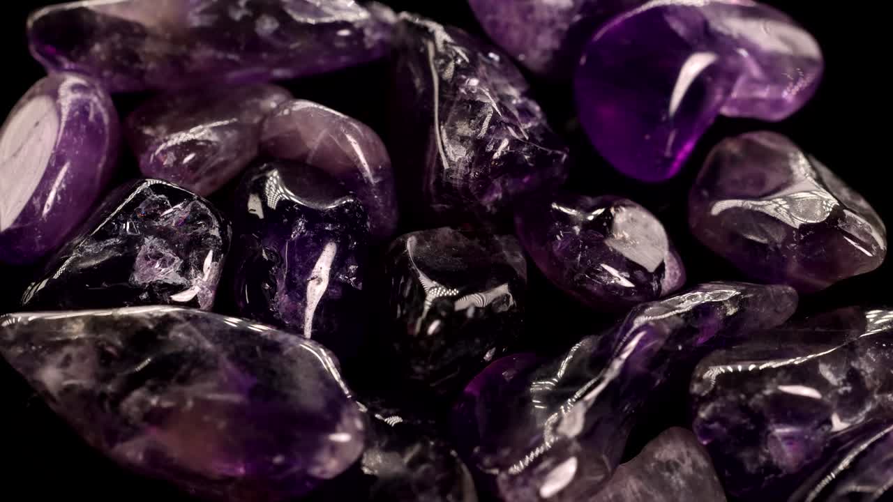 Close-up video of polished amethyst stones with shifting light, highlighting their rich purple hues and smooth textures