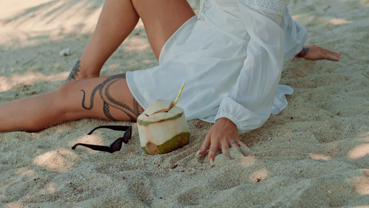 Woman relaxing on the beach with a coconut drink